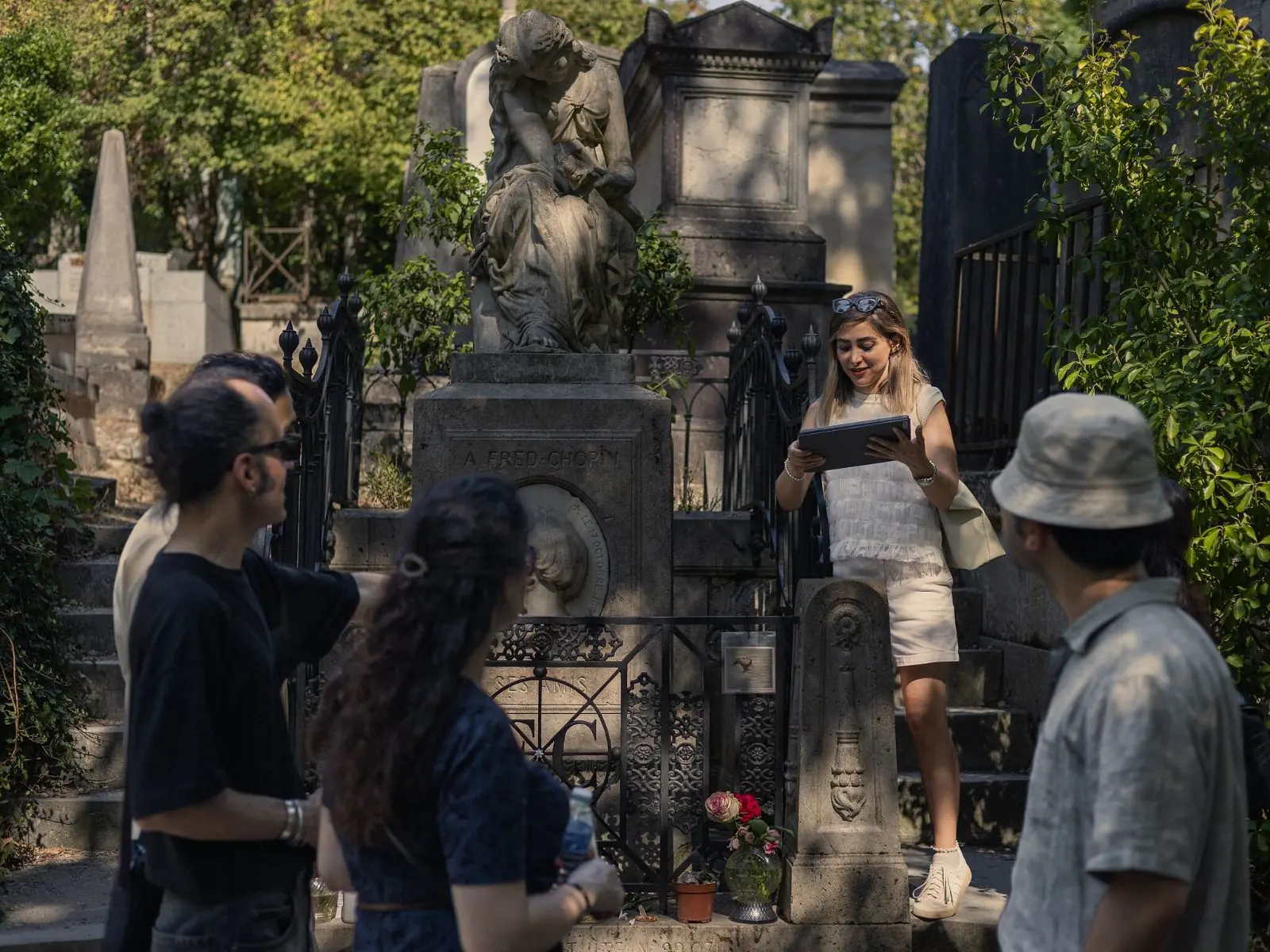 A guide talking to a small group in front of Chopin's monument, a seated muse in white marble