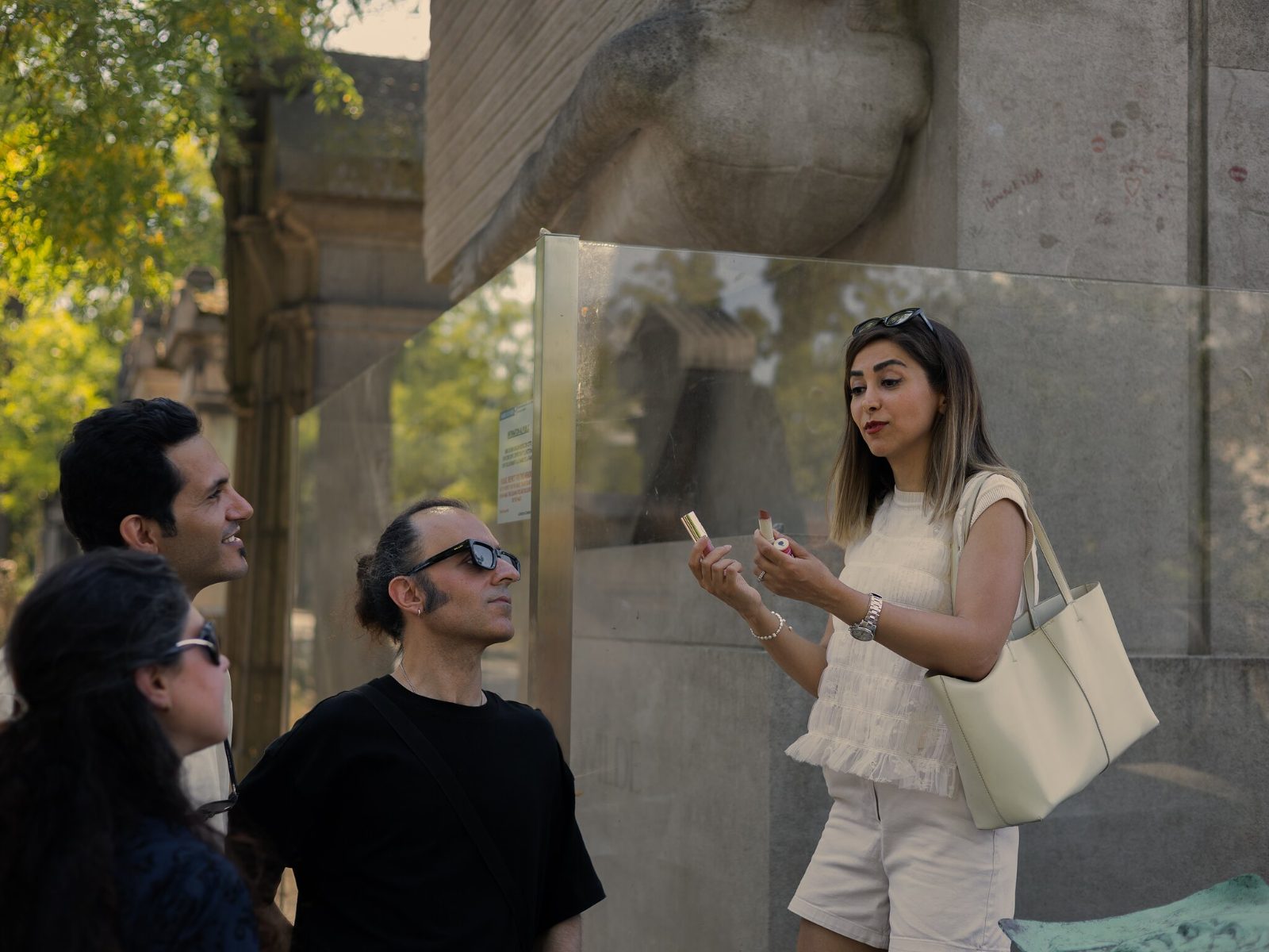 The glass barrier around Epstein's monument to Oscar Wilde, with a guide talking to visitors beside it